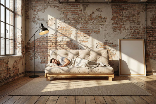 A man sleeping on a futon sofa
