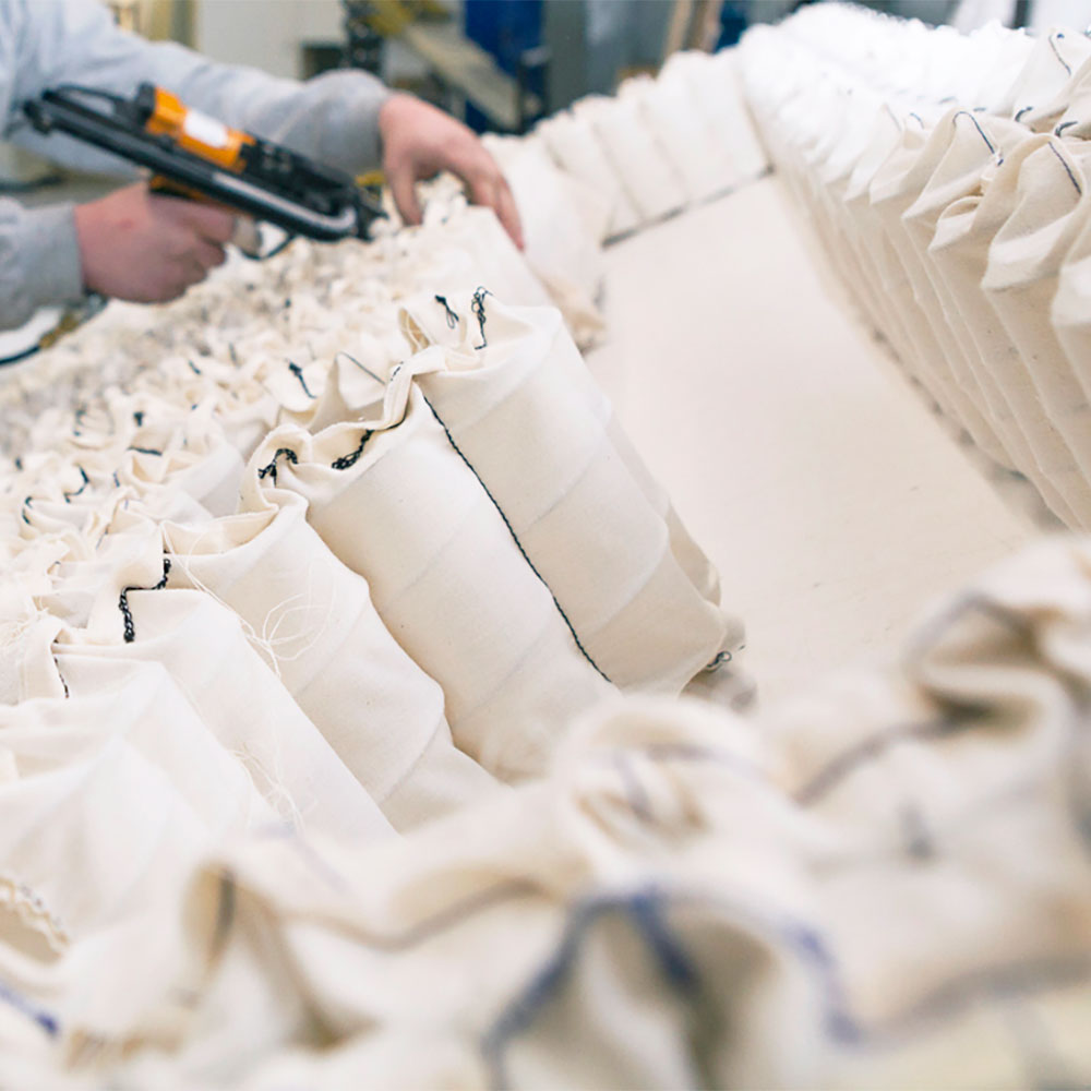 Close-up of white fabric rolls with a person using a tool in the background